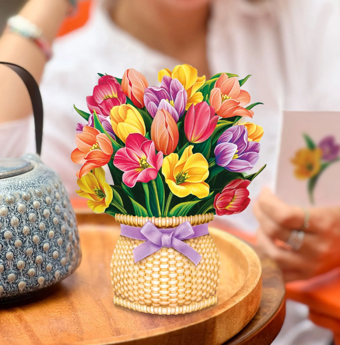 Colorful bouquet of flowers in a woven basket on a wooden table.