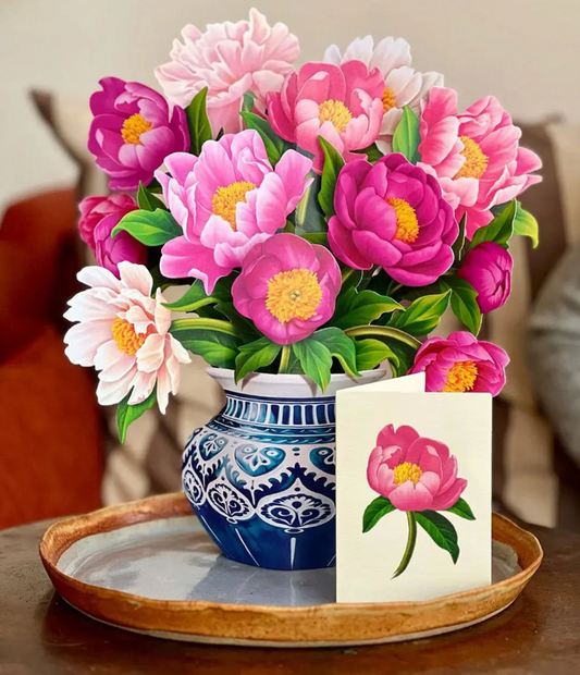 Bouquet of pink and purple flowers in a blue and white vase on a wooden tray with a matching card.