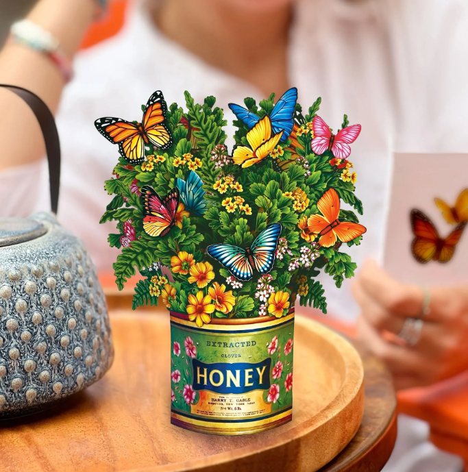 Honey jar with butterfly and flower design on a wooden table