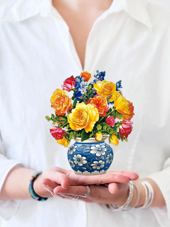 Colorful bouquet in a decorative vase held by a person wearing a white shirt.