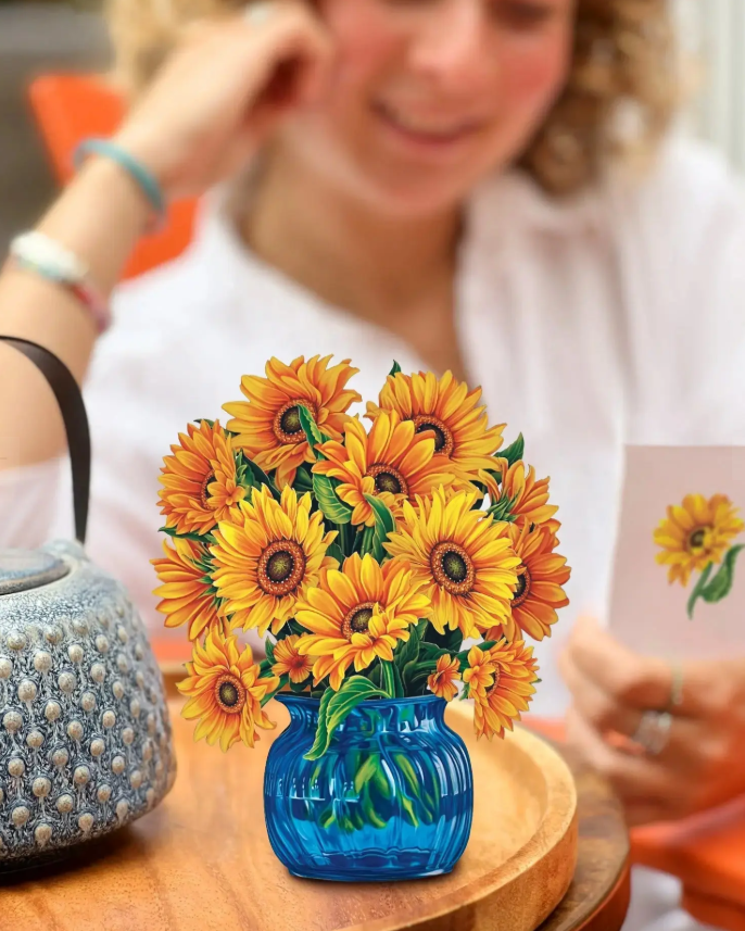 Vase with sunflowers on a table with a blurred person in the background
