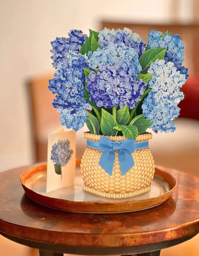 Decorative basket with blue flowers and a bow on a wooden table