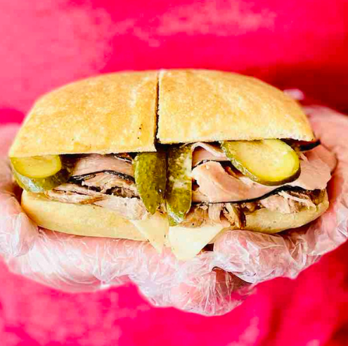 Sandwich with pickles and ham on a pink background