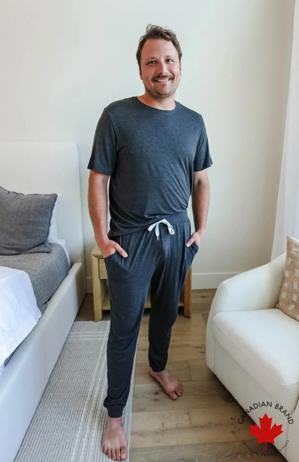 Man wearing a dark gray loungewear set standing in a living room.