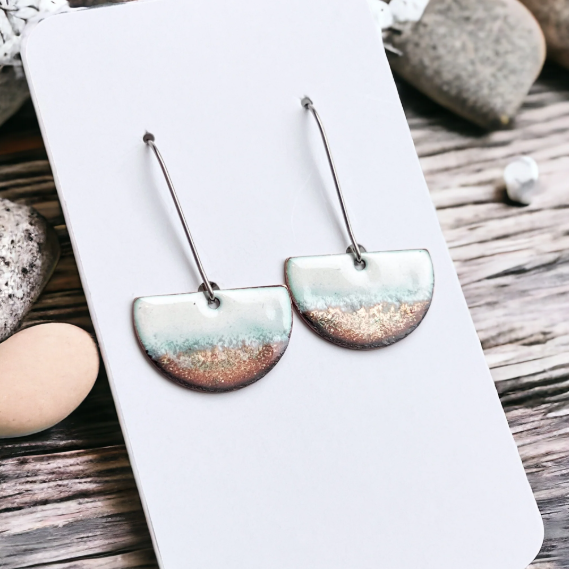 Earrings on a white card with pebbles in the background