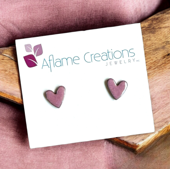 Heart-shaped earrings on a card with 'Aflame Creations Jewelry' branding, placed on a wooden surface.
