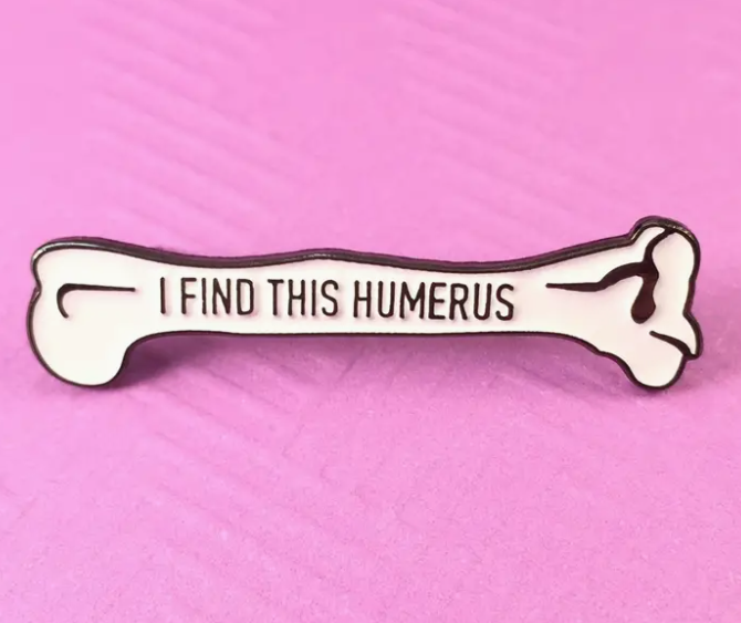 Pin with bone design and 'I FIND THIS HUMERUS' text on a pink background