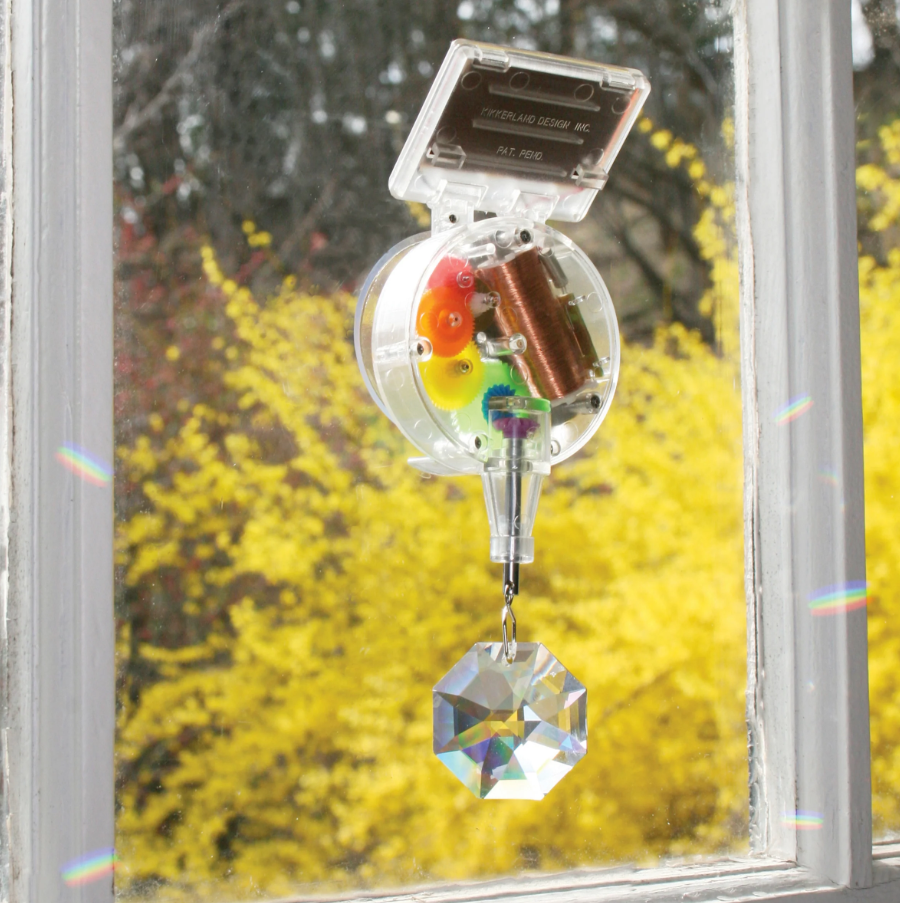 Window decoration with colorful prisms and a crystal hanging inside a window with yellow foliage outside.