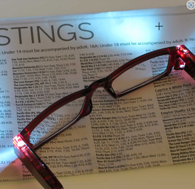 Red-framed glasses with LED lights on a movie poster background