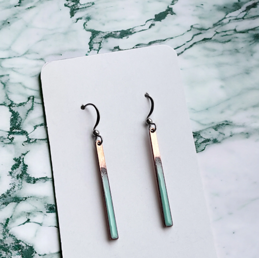 Pair of earrings on a white card with a marble background
