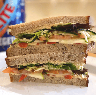Vegetable sandwich cut in half on a white plate with a blurred background